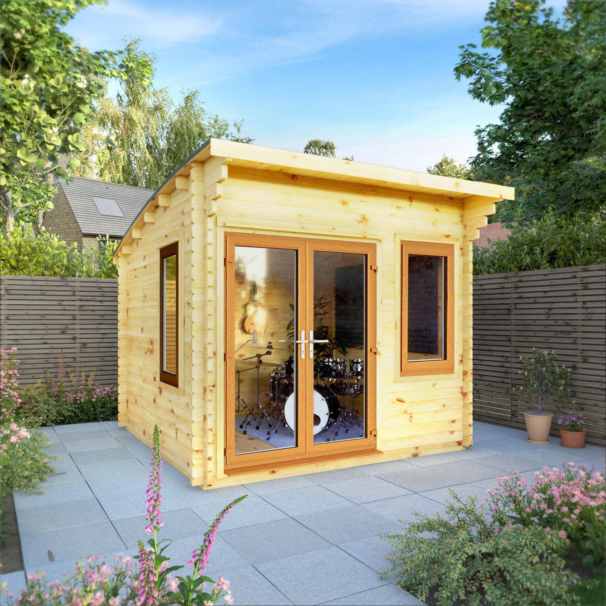 A curved roof log cabin with full length double doors and large windows, being used as a music room in a flowery British garden with oak UPVC